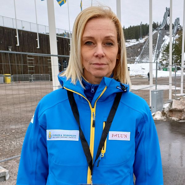 Ulrika Back, vd för Svenska Skidspelen, står utanför Lugnets skidstadion med tomma flaggstänger i bakgrunden