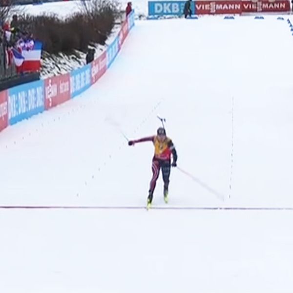 En skidlöpare firar i mål efter ett lopp på snö, med en tydlig bakgrund av en tävlingsarena och åskådare. I den delade delen av bilden visas en närbild av en person klädd i en mörk jacka, troligen en supporter eller medlem av laget.