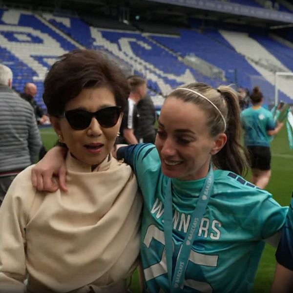 Tre personer i vinnart-shirts står tillsammans på en fotbollsarena efter matchen.
