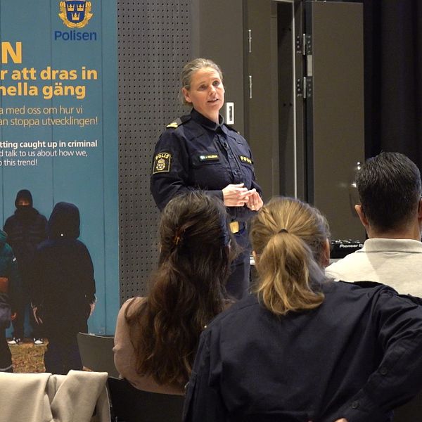 Polis håller föredrag för en grupp människor i ett konferensrum.