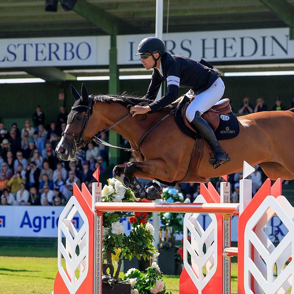 Ryttare hoppar över hinder med häst på hopptävling inför publik på Falsterbo Horse Show.