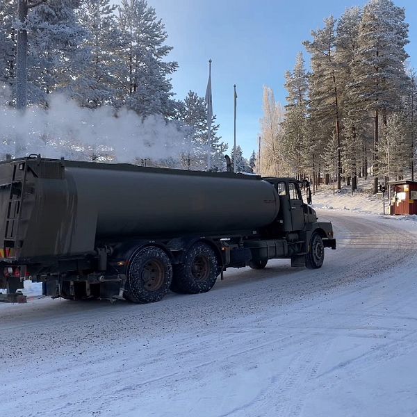 SVT:s reporter Sofie Lind till höger i bild och en militär tankbil utanför Älvdalens övningsområde till höger.