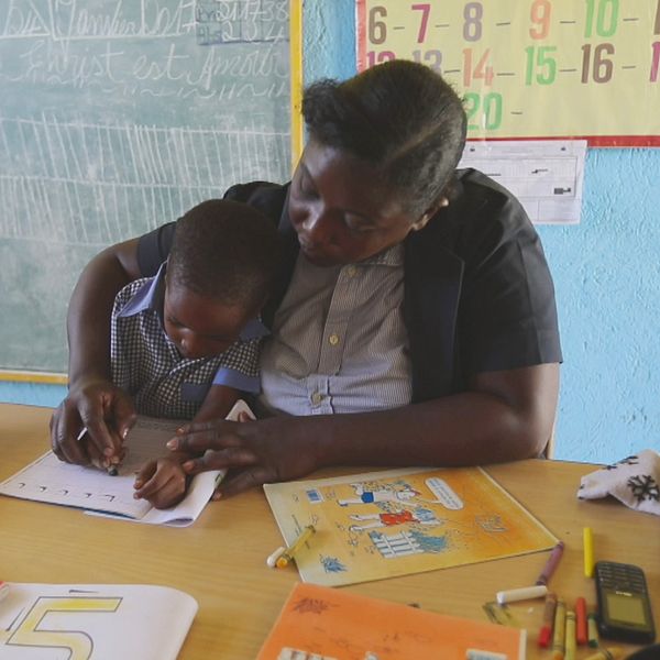 Kvinna lär ett barn skriva i ett klassrum på Haiti, Ulrika Kallin-Eriksson från hoppets stjärna.