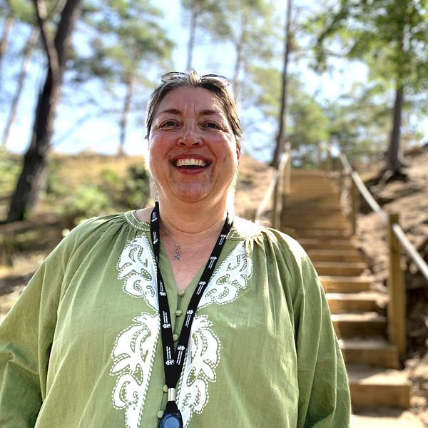 Annelie Ohlsson står framför trappan som leder upp till toppen av sanddynen. Trappan är insprängd mellan träden och sanden.