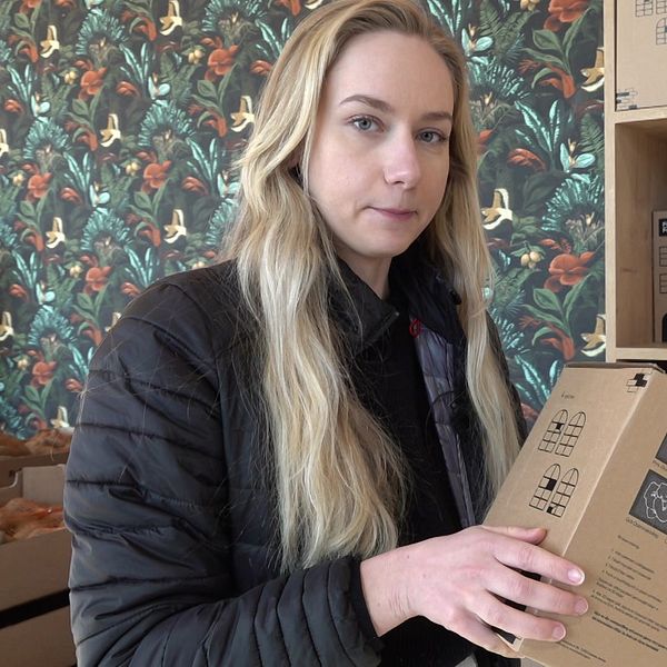 Person håller kaffeförpackning framför hylla med fler varuprover.
