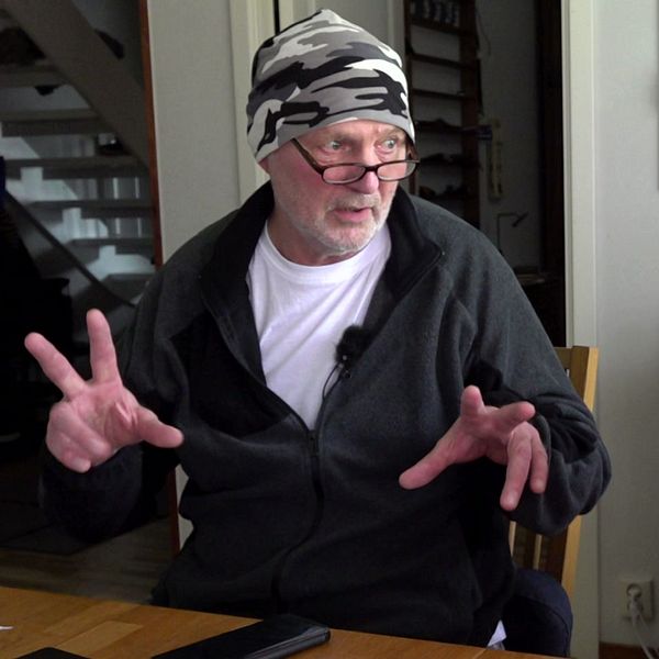 Person i konflikt från Sveriges värsta grannfejd gestikulerar och en annan man håller upp skylt utomhus.