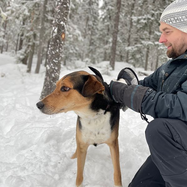 Hundägaren Christer Nilsson sitter med sin hund i snön i hundparken i Junsele