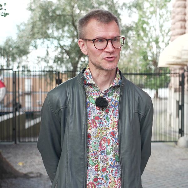 Jaakko Turunen står utomhus framför en byggnad med stora stenpelare