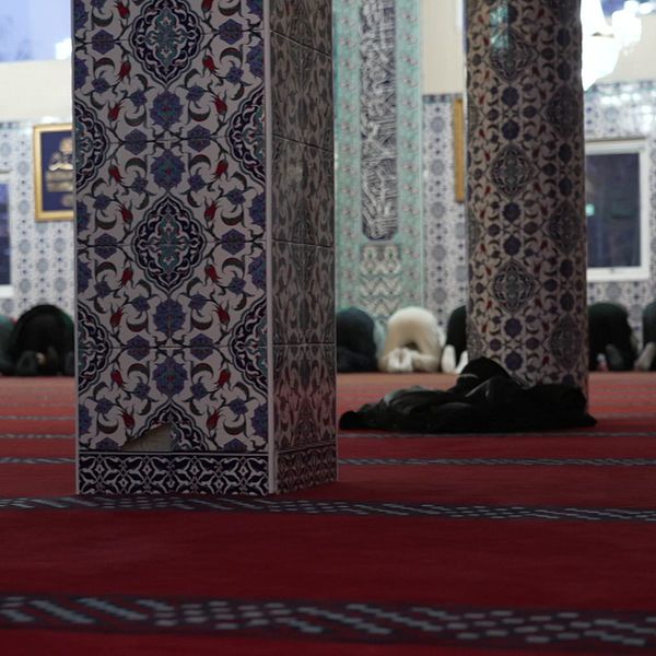 Bild inifrån en moské. en man tittar bortom kameran.