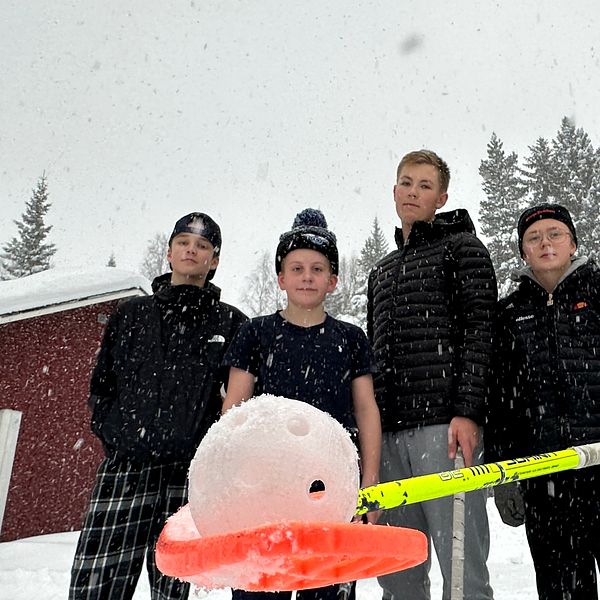 Fyra killar står bredvid varandra. En håller i en innebandyklubba där det vilar en boll på bladet.