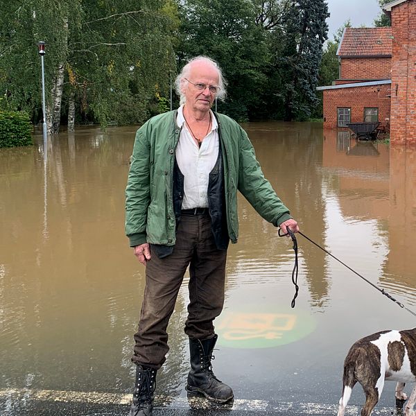 Man och en hund framför vatten.