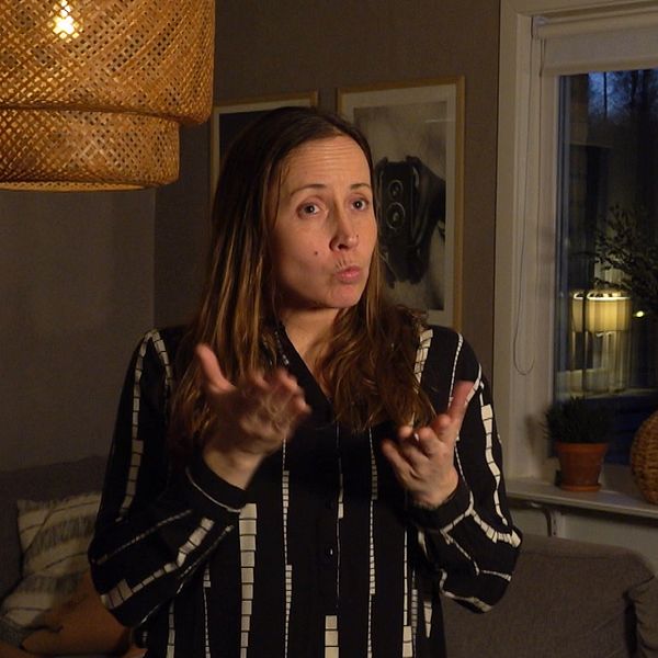 Martina Gedda i skjorta i vardagsrummet berättar om sin dotters situation på riksgymnasiet i Örebro