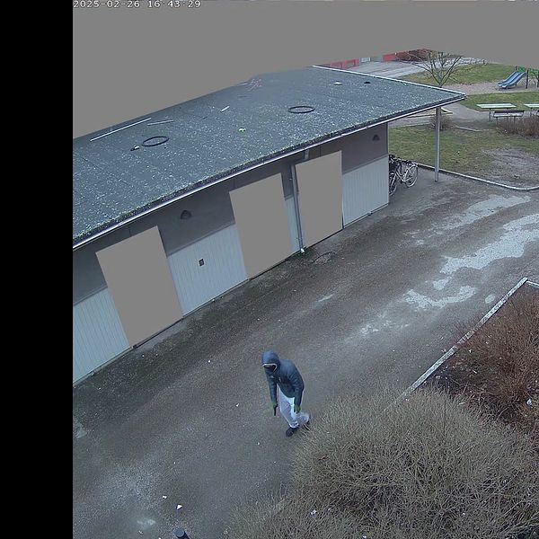 Öde gård med en person som promenerar förbi ett garage.
