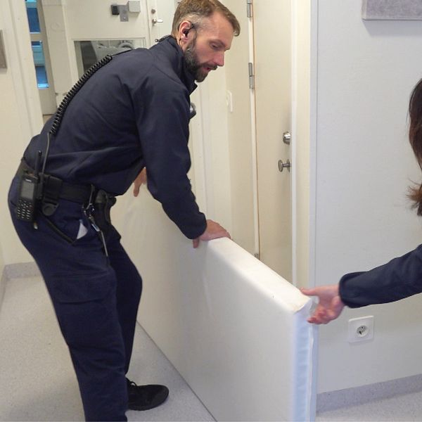 Två personer i personalen på Halmstad anstalt möblerar om och flyttar en vit madrass.