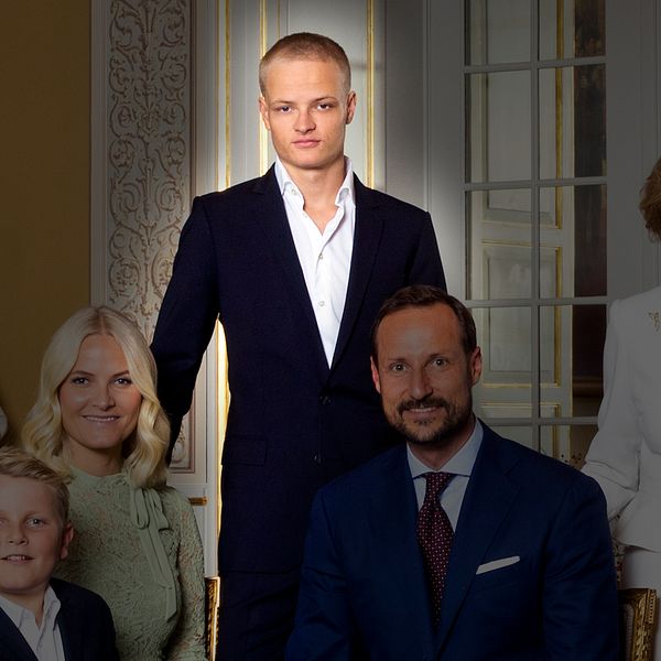Gruppfoto av norska kungafamiljen klädda i formella kläder, samlade i en elegant inomhusmiljö med ljusa väggar och stiliga inredningsdetaljer. En person (Marius Borg Høiby) står i mitten.