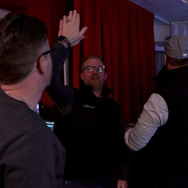 Flera personer ger varandra high five framför datorer i ett övervakningsrum.