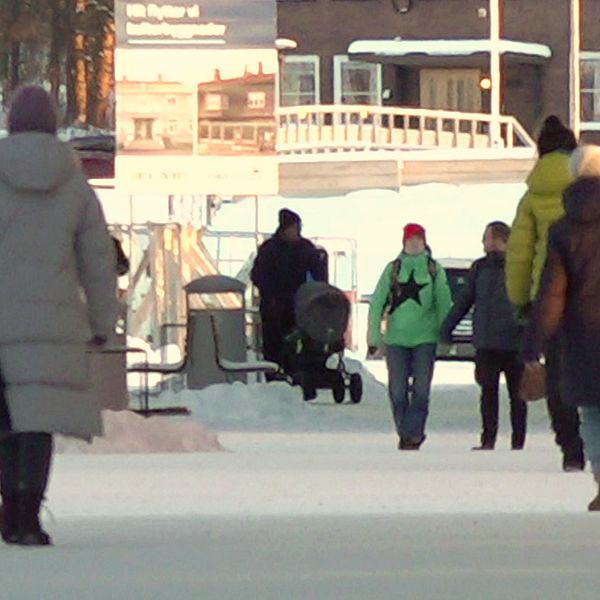 Flera personer på promenad i centrala Kiruna samt kommunalrådet Mats Taaveniku (S).