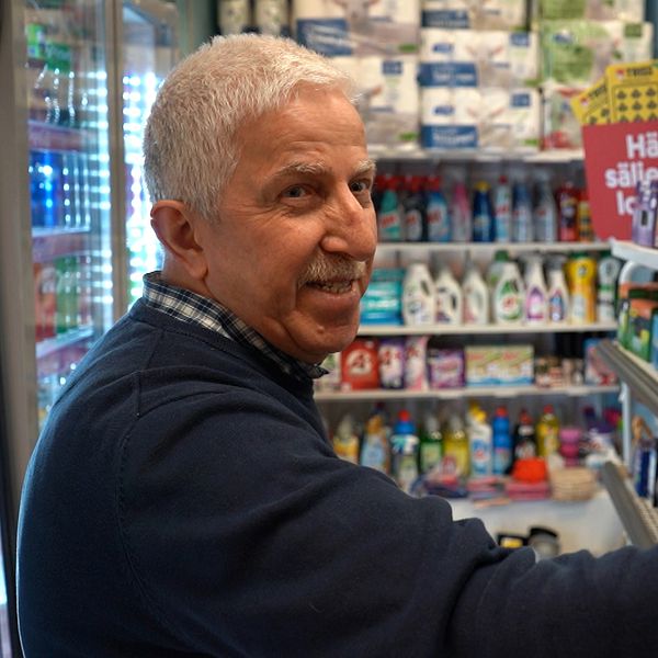 Man står framför butikshyllor med hushållsprodukter och livsmedel.