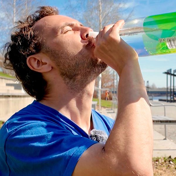 Daniel Brunell sitter på strandpromenaden och dricker vatten ur en flaska.