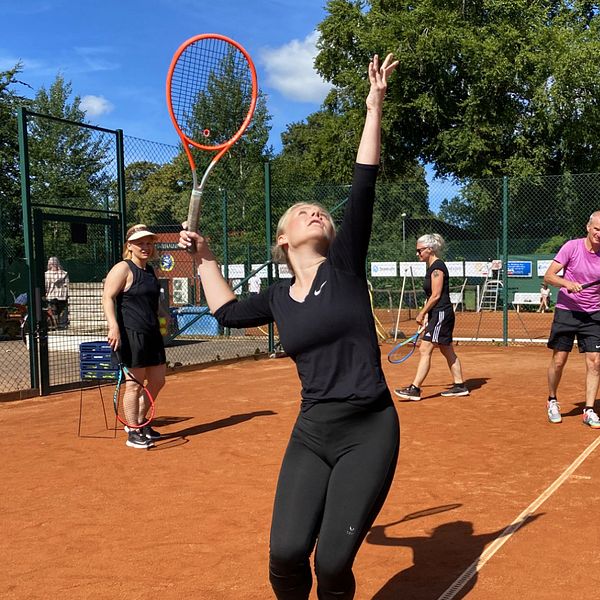 Tennisspelare kastar upp bollen och ska precis slå med sitt racket.