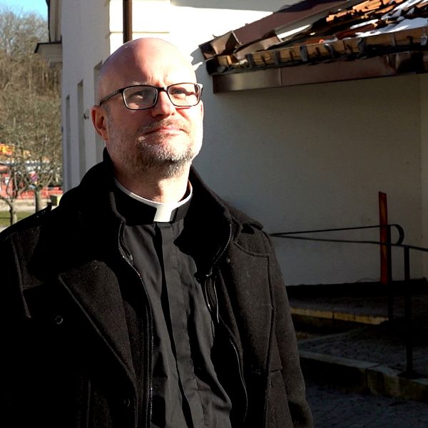 Patrik Ingemansson står i en prästkrage utanför Kyrkans Hus i Ronneby. Koppar har stulits från taket över entrén.