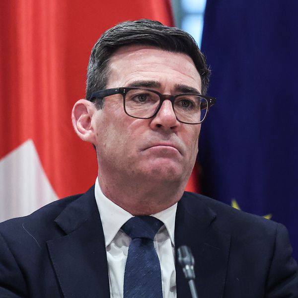 Andy Burnham framför Storbritanniens och EU:s flaggor