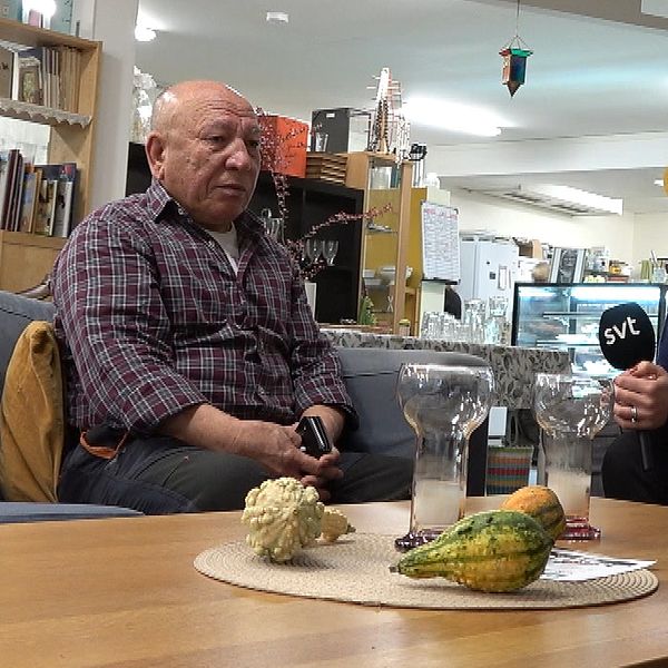 Gullahmad intervjuas av SVT i ett vardagsrum med glas och frukt på bordet.
