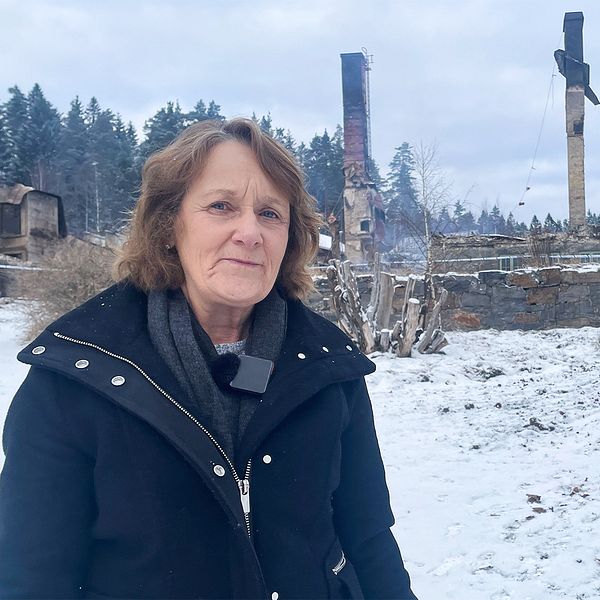 Gull-Britt Antonsson Söderberg står framför det nedbrunna sanatoriet i Rävlanda.