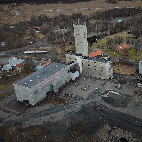 Flygbild av ett gammalt industriområde omgivet av skog och fält.