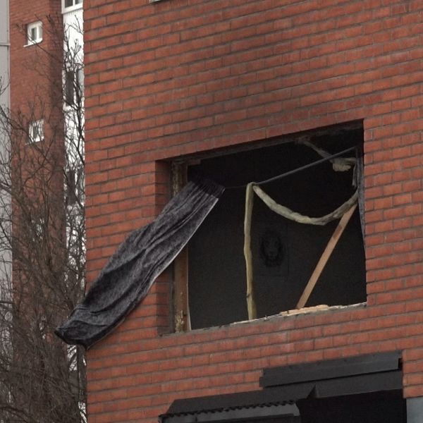 Bild på fönstret som fattas vid lägenheten i Sundsvall. Man ser en svart gardin sticka ut.