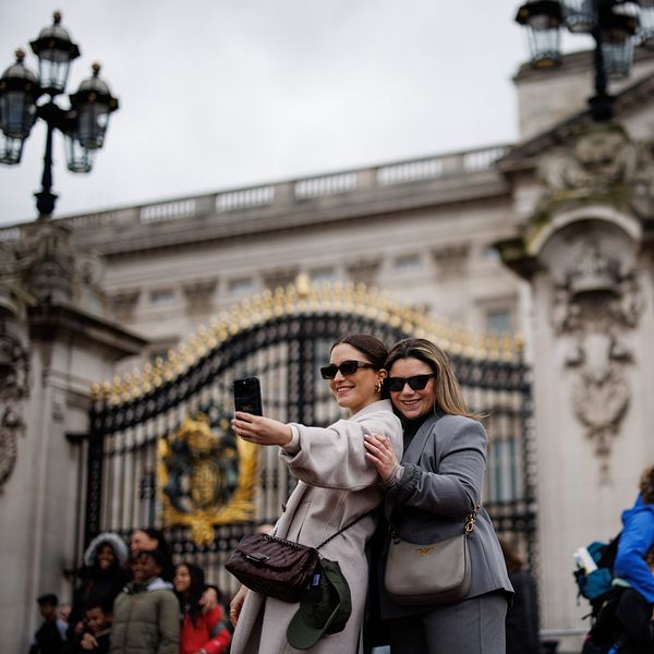 Två kvinnor tar en selfie framför Buckingham Palace.