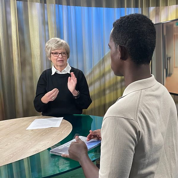 Sveriges dövas pensionärsförbund står och tecknar i en studio. Ryggtavlan syns på programledaren Abdi Mohamed och i skärmen bredvid dem visas en korridor med en äldre man som går med en rollator.