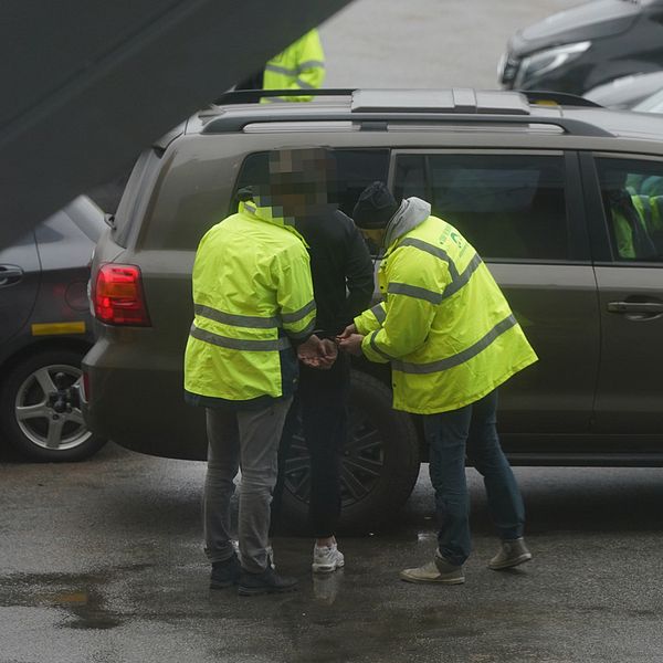 En man i handfängsel framför en bil