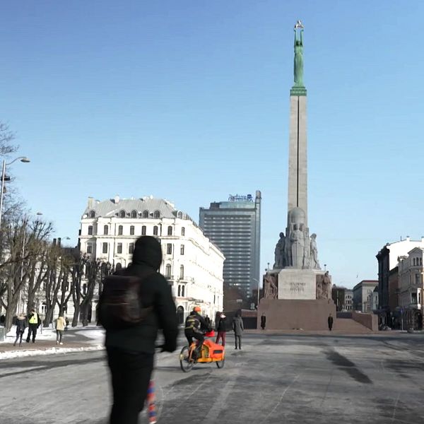 Torgplats med människor somn går och cyklar i Lettlands huvudstad Riga.