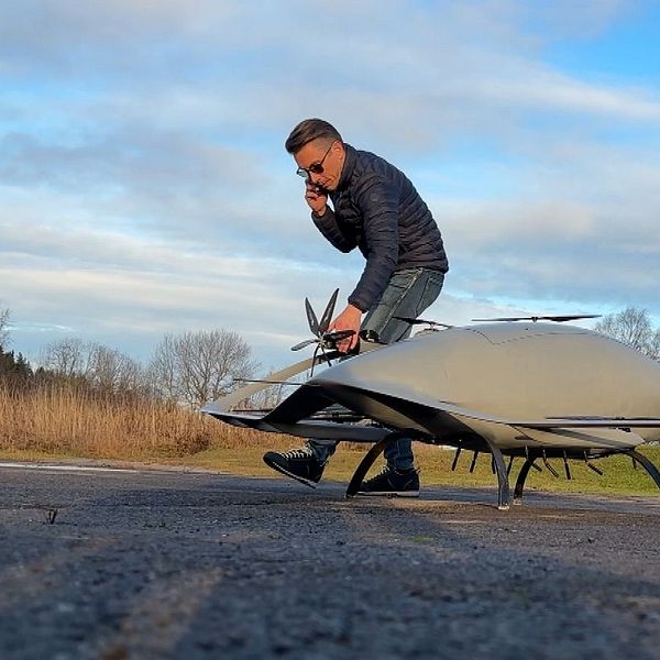 Michel Jansson inspekterar en drönare och pratar i telefon utomhus i Föllinge.