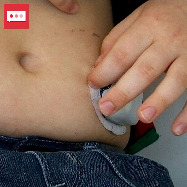 Ett barns hand justerar en insulinpump på magen.