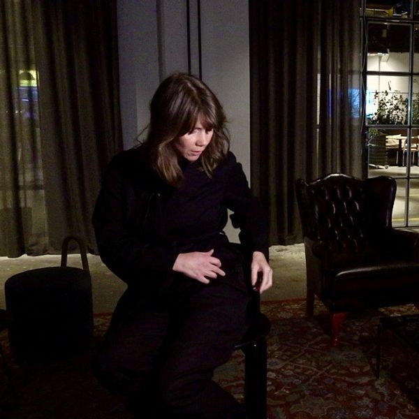 Tini Warg visar sina trasiga och otvättade byxor i en mörkt inredd lounge.