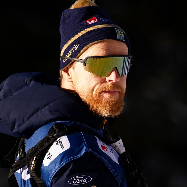 En delad bild som visar två personer i olika miljöer. Till vänster syns en person i vintersportkläder med en mössa, troligtvis en åkare eller tränare, och till höger en person i affärskläder som ser ut att delta i en intervju.