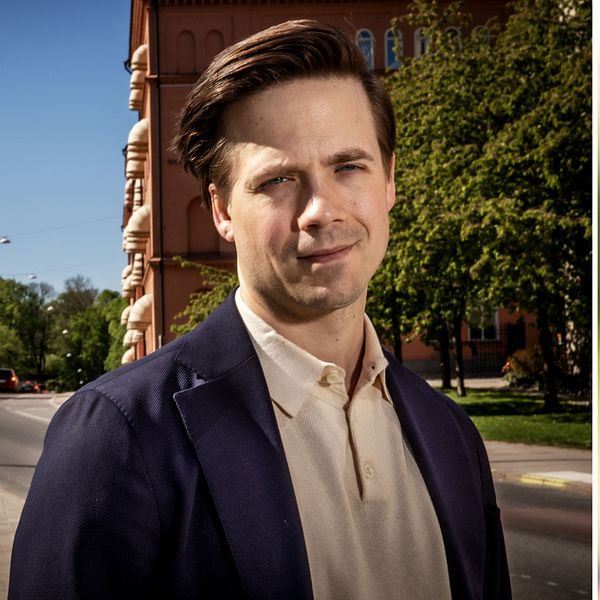 Man i kostym vid väg, med vattenkran och droppande vatten i bakgrunden