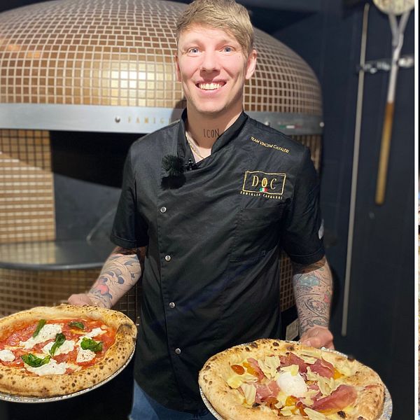 Vincent Cavaleri, pizzabagare står med två av sina nybakade pizzor. Tre pizzor på rad.