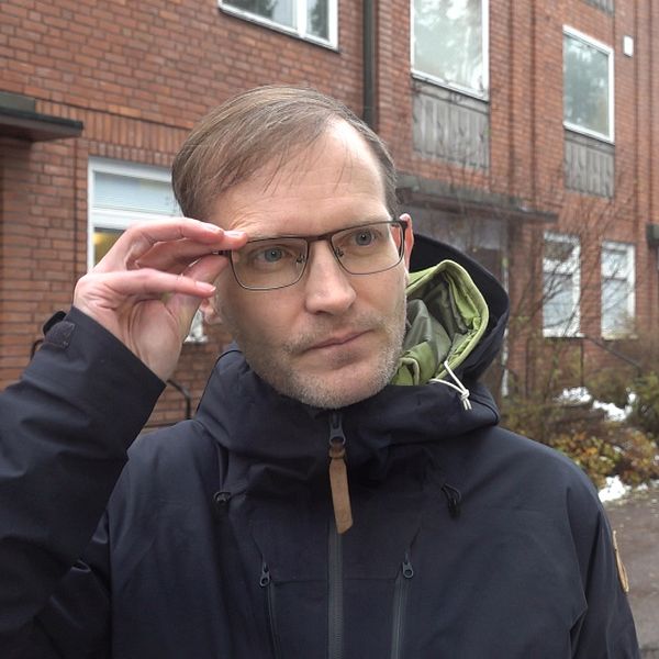 Smittskyddsläkaren Fredrik Rücker står utanför infektionskliniken i Falun, iklädd regnjacka och glasögon.