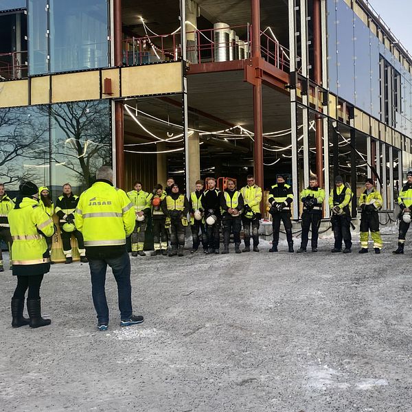 På bilden syns flera personer som är iklädda varselkläder på ett bygge i Härnösand. De har tagit av sina hjälmar och håller en tyst minut efter hissolyckan i Sundbyberg förra veckan.