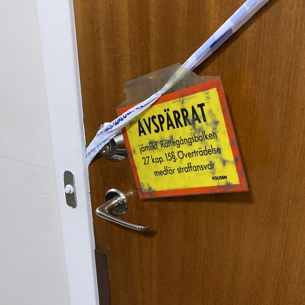 Dörren in till lägenheten som är avspärrad av polisen