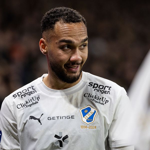 Fotbollsspelare i vit tröja på plan med en hörnflagga i bakgrunden.
