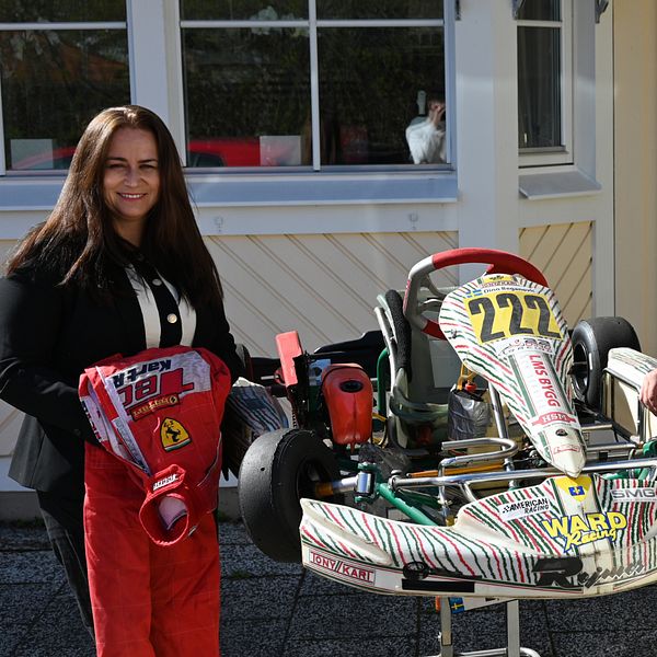 Två personer står bredvid en gokart utomhus framför ett hus.