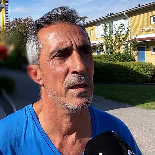 Man i kort hår intervjuas. Brandman sprutar vatten mot fastighet efter brand i radhus i Västerås.