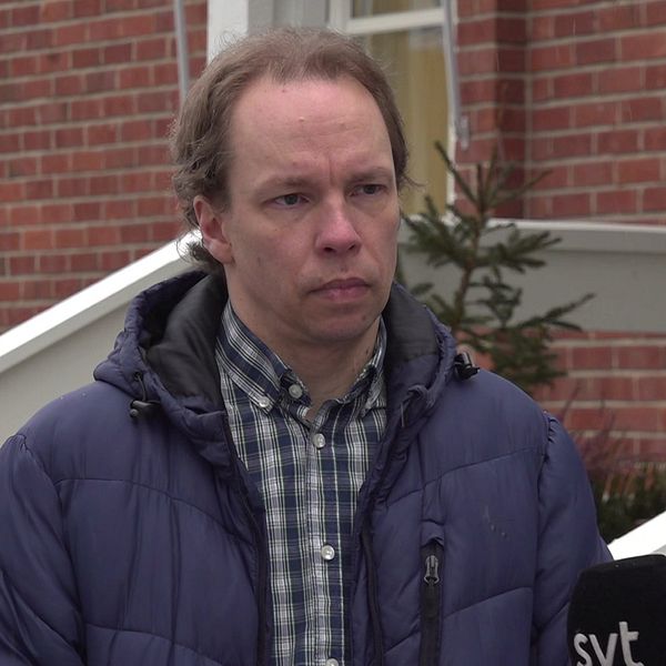 Reporter från SVT intervjuar person utanför tegelbyggnad.