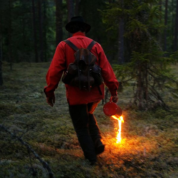 Man tänder eld på ris i skogen.