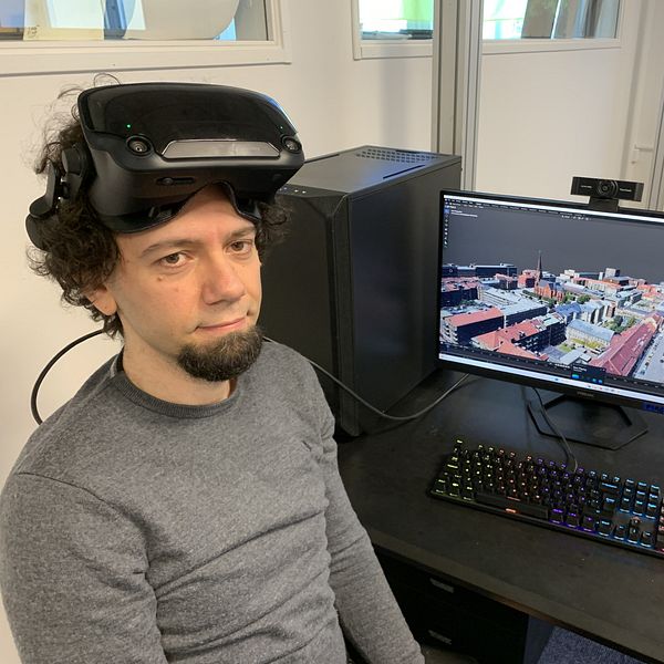 Man med VR-glasögon framför en dator