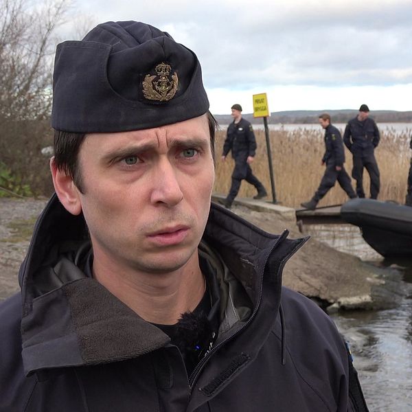 Kapten Karl Ekman framför röjdykare och en gummibåt i strandkanten